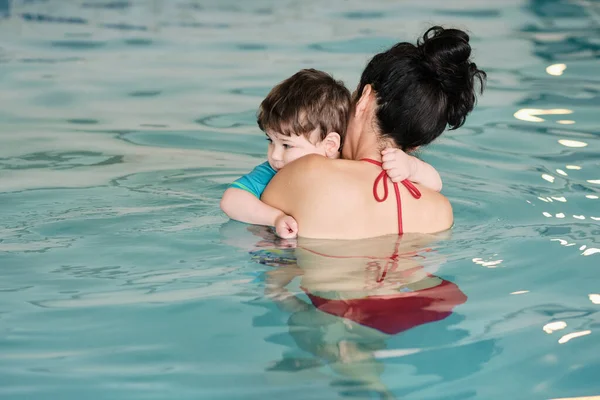 little boy in the pool being held by his mom
