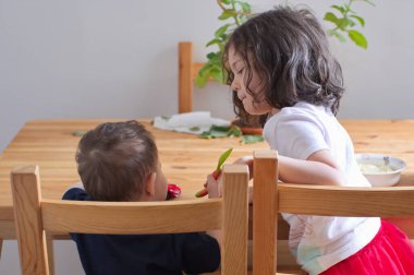 Kardeşler kahvaltı masasında oynaşıyor.