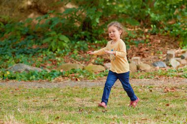 Parktaki çim tarlasında koşan tatlı genç kız.