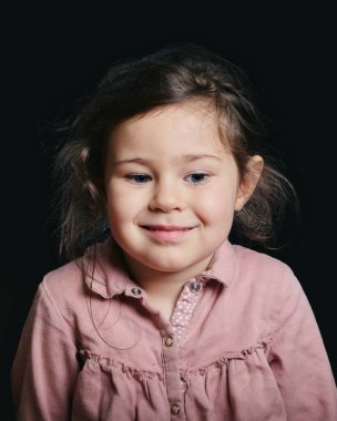 Stüdyoda siyah bir arkaplan karşısında etkileyici suratlar yapan hoş bir kız.