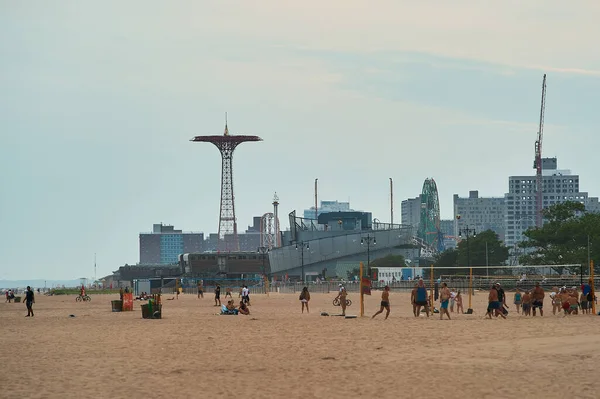 Coney Island sahilinde voleybol oynayan insanlar bulutlu bir akşamda