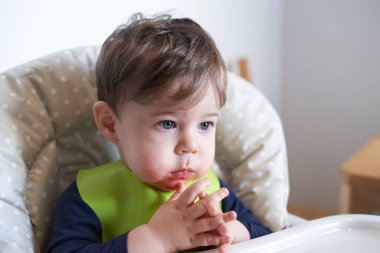 Küçük bebek yüksek sandalyede domates yiyor.