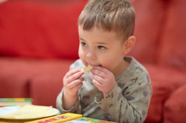Kanepenin yanında televizyon izlerken evde peynir yiyen tatlı çocuk.
