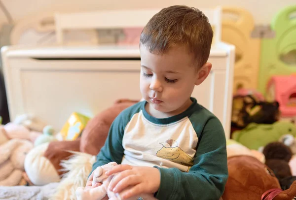 可爱的小男孩在一堆堆柔软的毛绒玩具中玩耍 — 图库照片