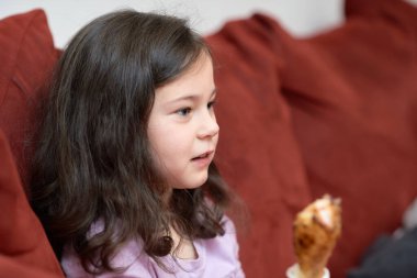 Ekspres genç kız TV izlerken akşam yemeği için kanepede tavuk ve sebze yiyor.