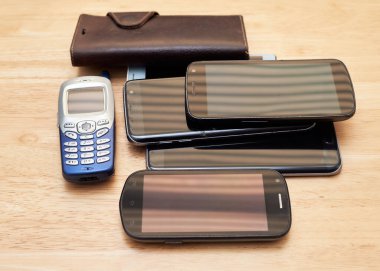 Masaya yığılmış onlarca yıldan kalma kullanılmış cep telefonları.