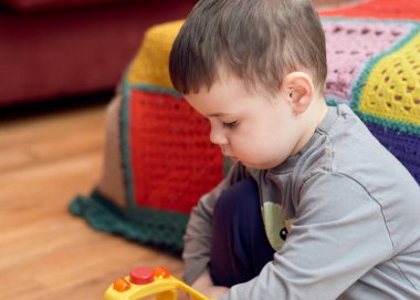 Genç çocuk evde oyuncaklarla oynuyor.