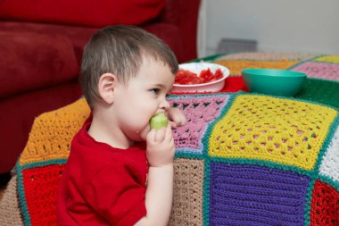 TV izlerken salatalık ve domates yiyen tatlı çocuk.