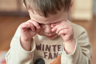 Küçük çocuk ağlıyor ve gözlerini ovuyor.