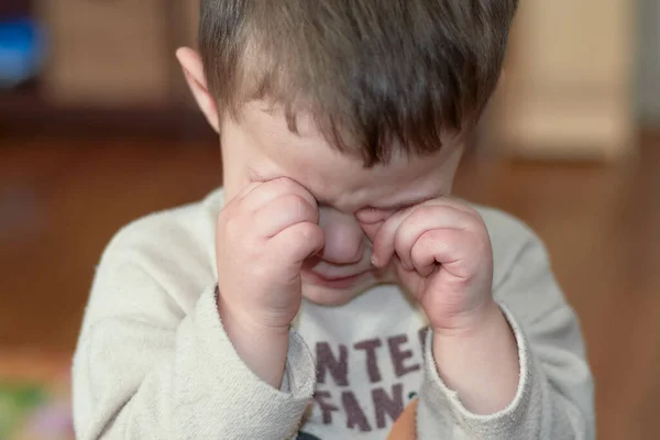 little boy crying and rubbing his eyes