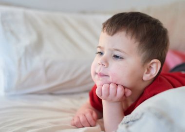 Bebek, yatakta televizyon seyrediyor. Yüzü çilek suyu içinde.