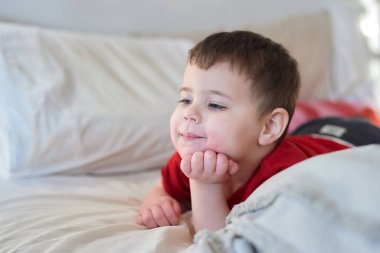 Bebek, yatakta televizyon seyrediyor. Yüzü çilek suyu içinde.