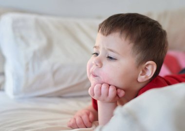 Bebek, yatakta televizyon seyrediyor. Yüzü çilek suyu içinde.