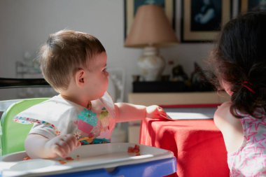 Küçük şirin çocuk öğle yemeğinde sandalyesinde domates yiyor.