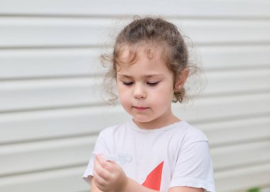 Güzel genç kız arka bahçede sabun köpüğüyle oynuyor.