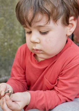 Garajın arka bahçesinde dallarla oynayan tatlı bir çocuk.