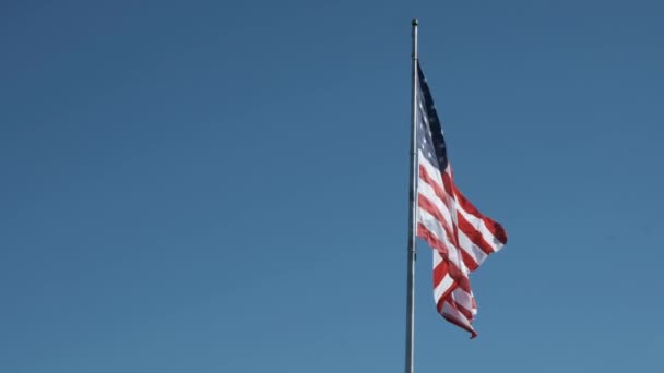 カップルの賢明な雲と澄んだ青い空に対して設定されたスローモーションで極に振っている米国の旗 — ストック動画