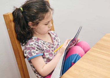 Mutfak masasında matematik bilmeceleri çözen tatlı bir kız.