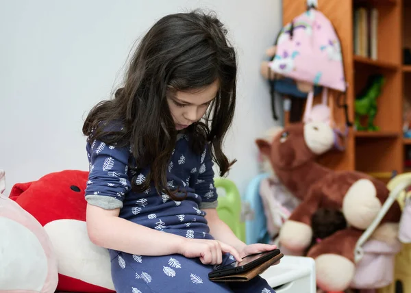 stock image cute young girl is playing games on a cell phone at home