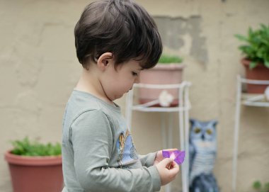 Kardeşler arka bahçede mor bir çiçekle oynuyorlar.