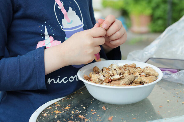 Молодая девушка обстреливает арахис в тарелку на заднем дворе