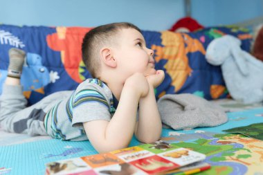 cute young boy reading a book with animal picutres