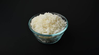 Siyah arka planda cam bir kasede küçük bir porsiyon basmati pilavı.