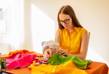 Kadın evde çalışıyor, dikiş makinesi kullanıyor.. 