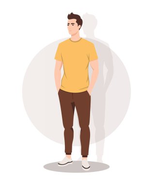 Sarı tişört ve kahverengi pantolonu olan sıradan bir kıyafet giymiş genç bir adam. Rahat bir duruş sergiliyor, her gün zahmetsiz ve şık bir görünüm sergiliyor..