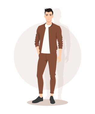 Topraksı kahverengi bir ceket ve bej pantolon giymiş genç bir adam, sıcak ve rahat bir sonbahar kıyafetini somutlaştırıyor..