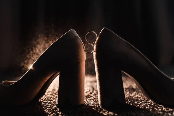 Золотые Обручальные Кольца Темном Фоне Отражением Свадебных Туфель Легкой Брызг — стоковое фото