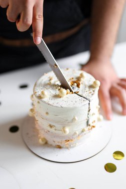 Bu fotoğrafta, muhteşem bir pasta yapmak için çalışan bir pasta şefi görüyoruz. Elleri malzemeleri ustalıkla manipüle ederek onlara gerekli şekli ve dokuyu veriyor. Etrafında.