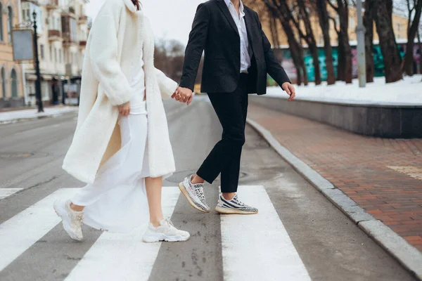 新娘带着结婚花束和新郎回到人行道上 手牵着手沿着城市的街道散步 外面的新婚夫妇 高质量的照片 — 图库照片