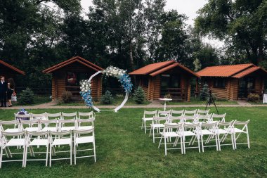 Güneşli bir yaz gününde, bir gölün kıyısında, dağların arka planında madalyalı bir düğün kemeri. Dış mekan düğün töreni için dekorasyon. Yüksek kalite fotoğraf