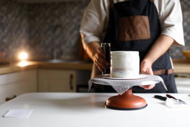 Bu fotoğrafta, muhteşem bir pasta yapmak için çalışan bir pasta şefi görüyoruz. Elleri malzemeleri ustalıkla manipüle ederek onlara gerekli şekli ve dokuyu veriyor.. 