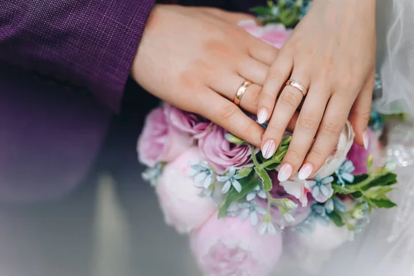 手拿结婚戒指 新娘和新郎的手 戴着结婚戒指和新娘花束 新郎轻轻地握住新娘的手 高质量的照片 — 图库照片