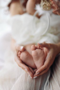 Anne, bebeklerin bacaklarını elinde tutuyor. Anne ve çocuğu. Mutlu aile kavramı. Anneliğin güzel konsept görüntüsü. Yüksek kalite fotoğraf