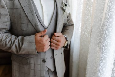 Adam düğmeleri bağlar. Takım elbiseli damat. Kapatın. Adam yeleğinin düğmelerini ilikliyor. En ince ayrıntısına kadar mükemmel. Modern iş adamı. Zarif klasik takım elbiseli yakışıklı bir gencin moda fotoğrafı.. 