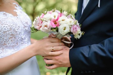 Gelin ve damat yan yana duruyorlar ve mavi takım elbiseli, papyonlu bir adam nazikçe onu omuzlarından tutuyor.. 