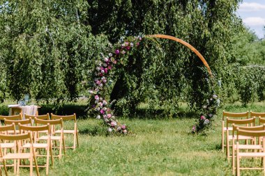 Düğün için yuvarlak kemer beyaz çiçekler ve yeşillik ile süslenmiştir. Gelin ve damadın düğün hazırlıkları ahşap bölgedeki parkta yapılacak. - Evet. Yüksek kalite fotoğraf