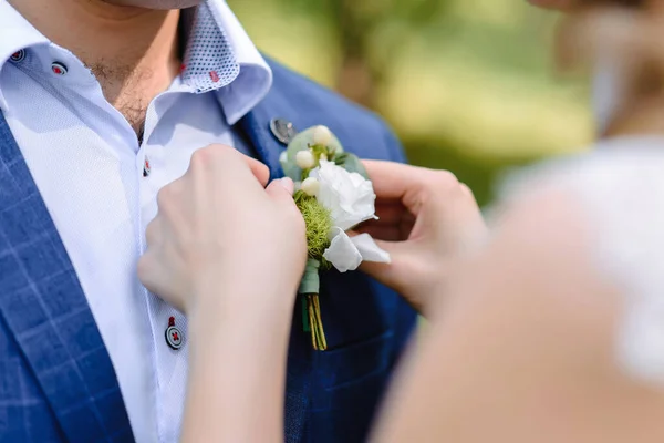 bride puts boutonniere on grooms jacket, wedding, couple. High quality photo