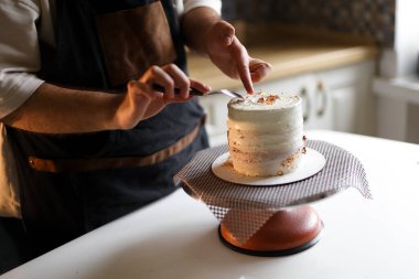 Hayranlık uyandıran bir pasta: profesyonel pasta şefi onu zevkle süslüyor. Yüksek kalite fotoğraf