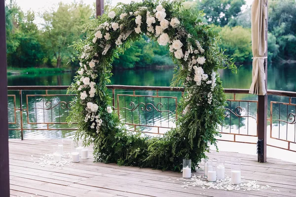 beautiful wedding arch on the pier overlooking the sea. modern round wedding arch with candles and flowers. Wedding decorations. High quality photo