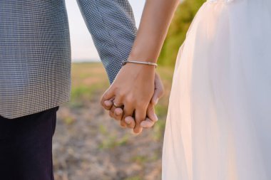 Çiftler gün batımında yeşil alanda el ele tutuşuyorlar. Yüksek kalite fotoğraf