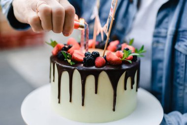 Kıtır kıtır pastalı ve mini kremalı bir tatil pastası. Adam pastaya mum yakıyor. Mumlu doğum günü pastası. 