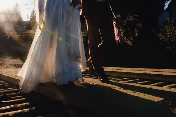 在日落时走在木桥上的新婚夫妇 高质量的照片 — 图库照片