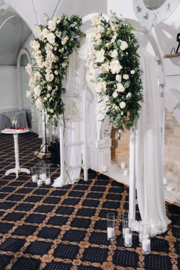 Restoranda düğün kemeri. Yuvarlak çiçek kemeri. Düğün ziyafeti odasındaki trend, arka plandaki beyaz örtüde çiçekler ve yeşilliklerle süslenmiş beyaz bir kemer. Yüksek kalite fotoğraf