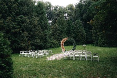Düğün töreni. Çok güzel ve şık bir düğün kemeri, çeşitli taze çiçeklerle süslenmiş, bahçede duruyor. Düğün günü. Taze çiçek süslemeleri, şakayıklama. Yüksek kalite fotoğraf