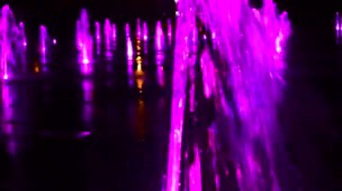 Parktaki havuz aydınlandı. Su akıntıları, renkli ışıklar. Gece şehri.