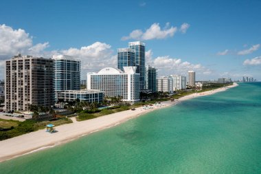 İnsansız hava aracı manzarası, arka planda binalar, güzel mavi gökyüzü ve plaj, dalgalar, tatil
